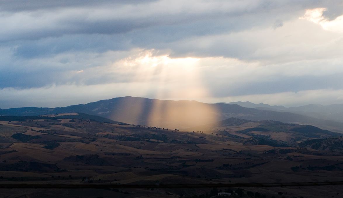 Sunshine through parted clouds over rural landscape