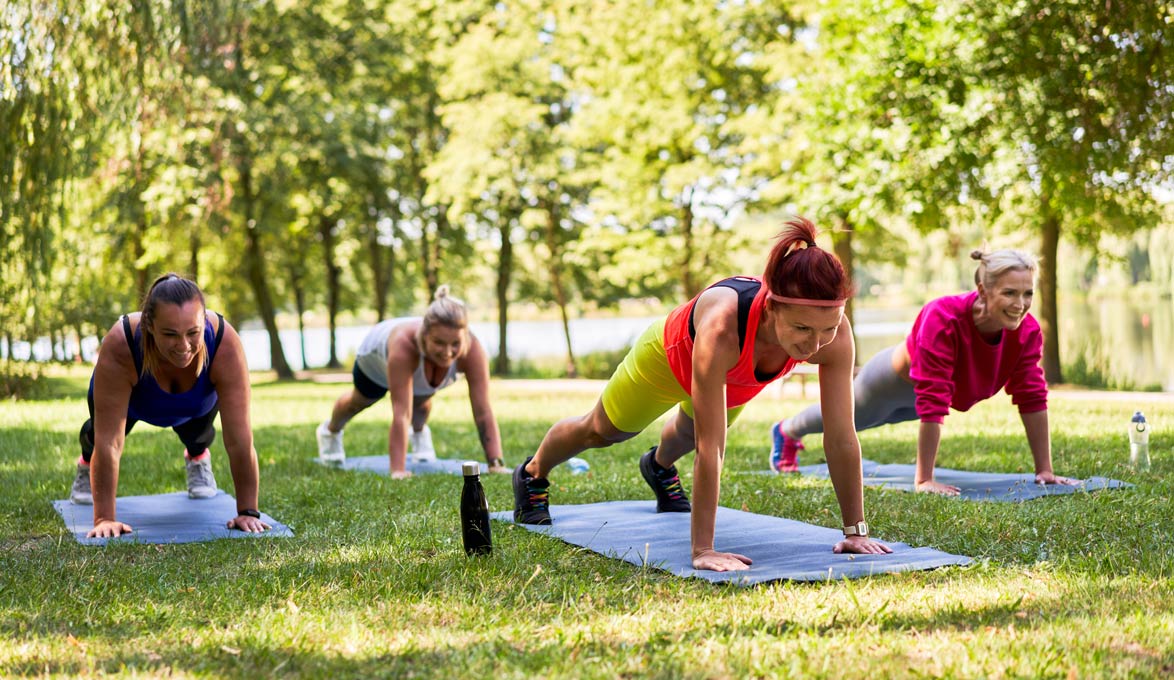 middle-aged women practicing yoga in a park