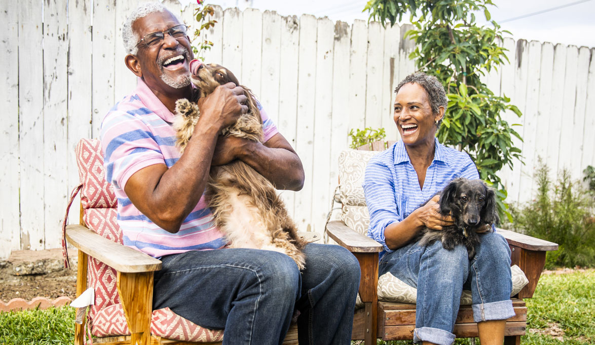 Couple cuddling with dogs in backyard