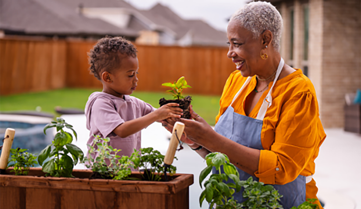 Grandmother planting flower bed with grandchild