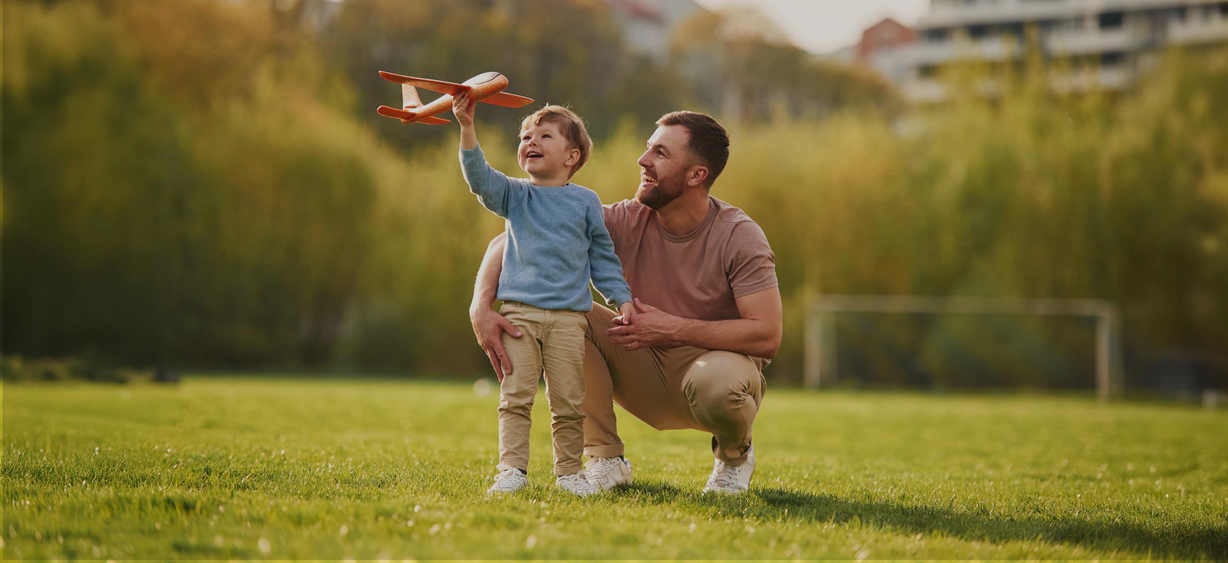 Man and his child playing with airplane toy in the park