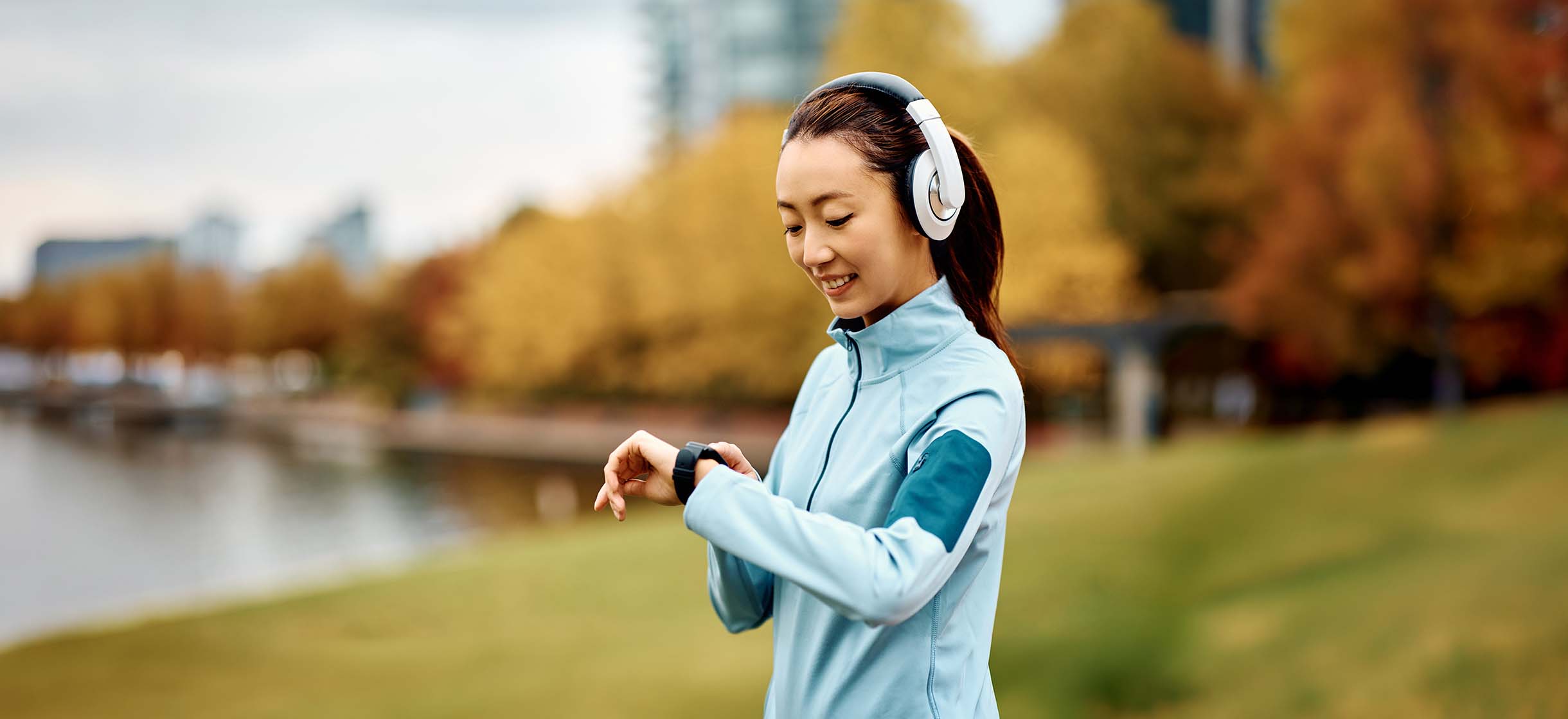 A woman wearing headphones and checking her smartwatch