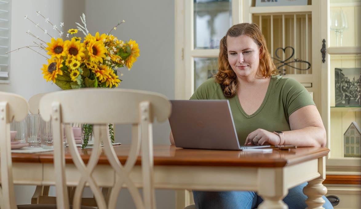 A woman using a laptop at her kitchen table