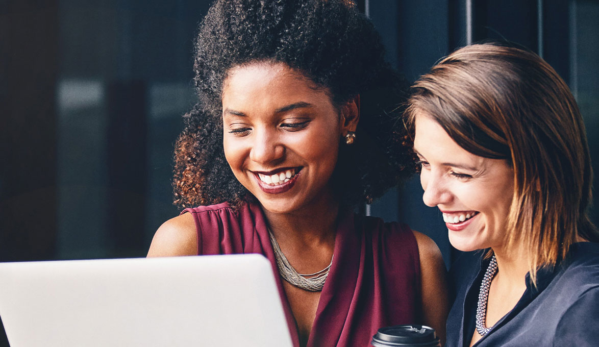 Two business women looking at a laptop discussing small business loan options