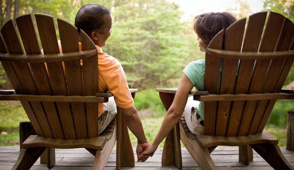 Couple sitting outside holding hands.