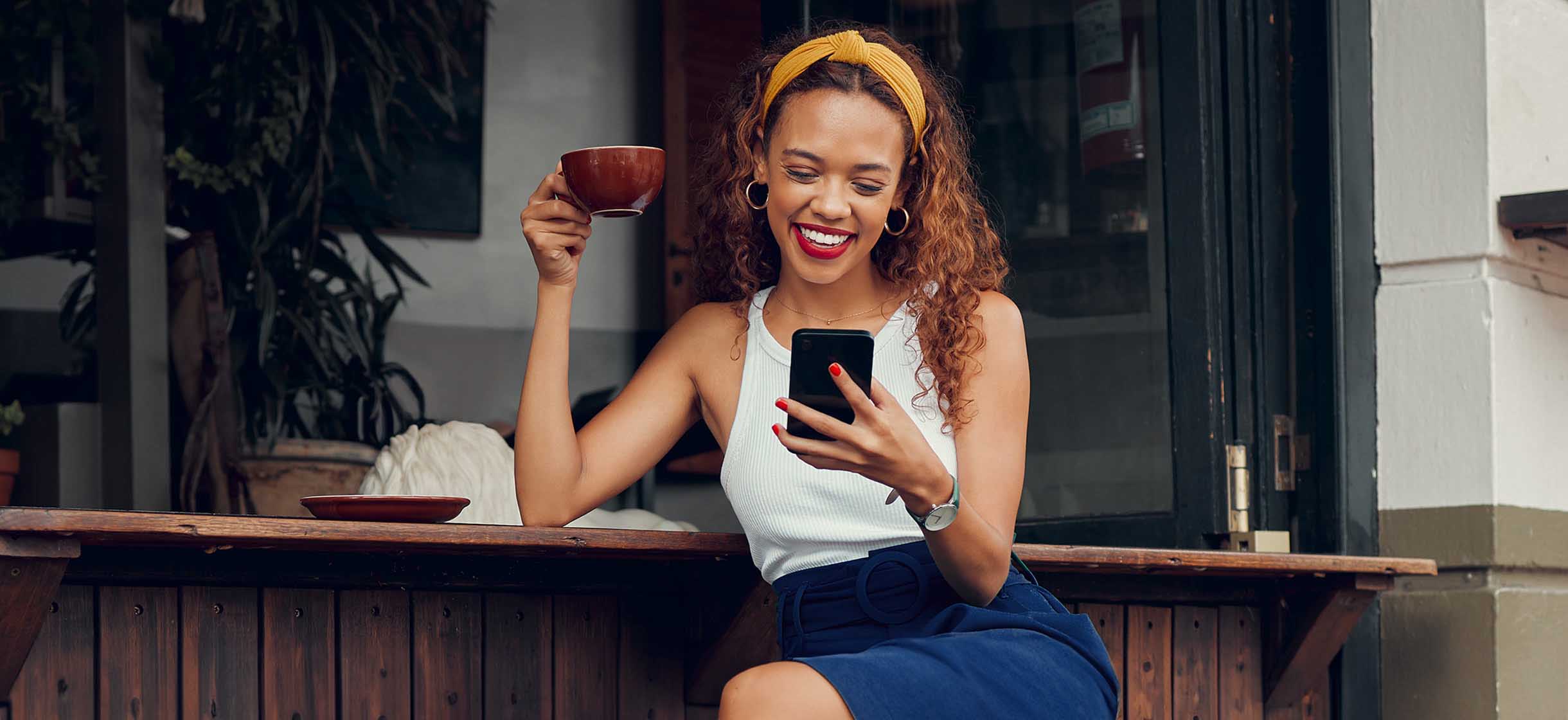 A woman at a cafe reviews her online banking app