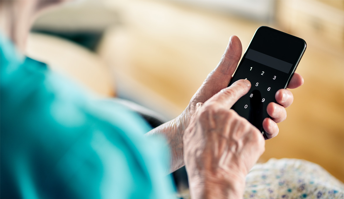 Elderly person entering PIN on phone
